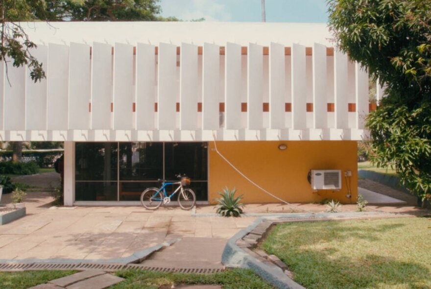 The exterior of a building with vertical white shutters along the top. 