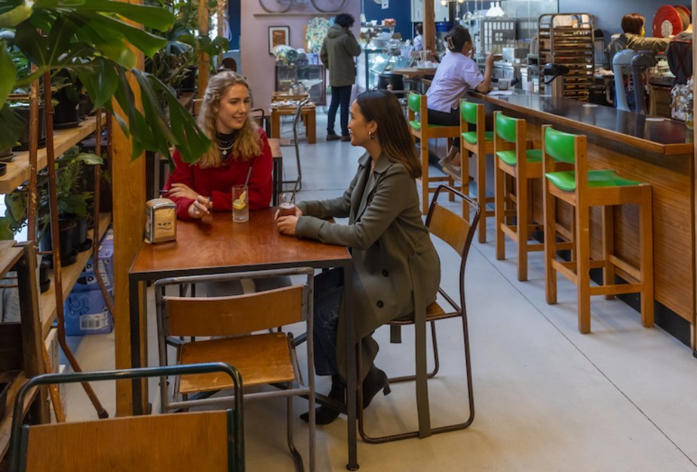 Two people at a dining table in an cafe.