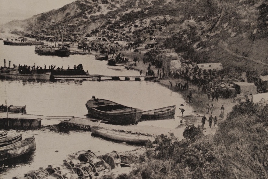 Boats docked at Gallipoli harbour with troops massed on shore.