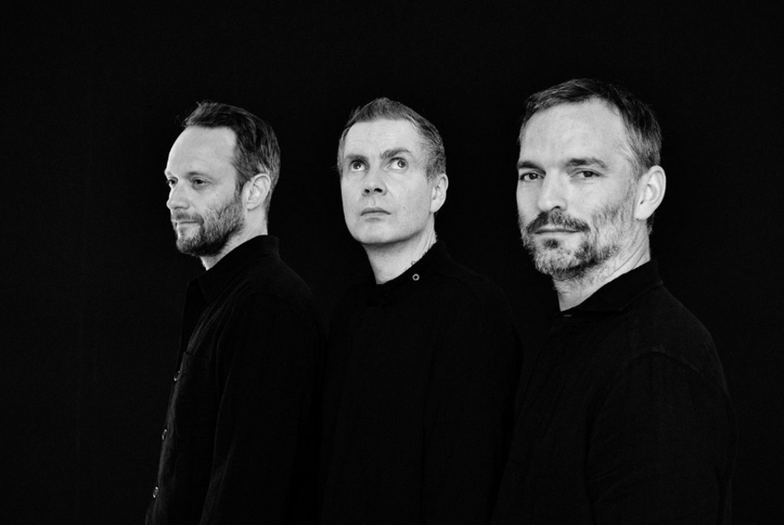 The three members of the band Sigur Ros all looking in different directions, wearing black shirts, posed against a black background.