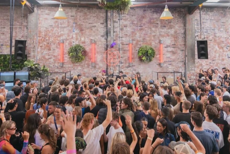 A crowd of dancers in a brick factory setting.