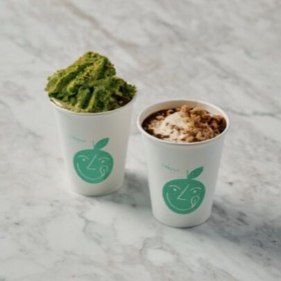 Matcha and regular hot chocolate takeaway drinks on a marble counter.