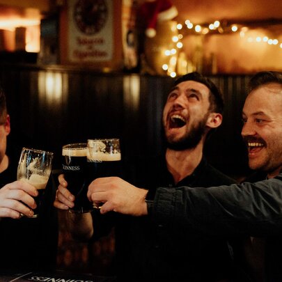 Three friends laughing and enjoying Guinness pints at P.J. O'Brien's Irish Pub.