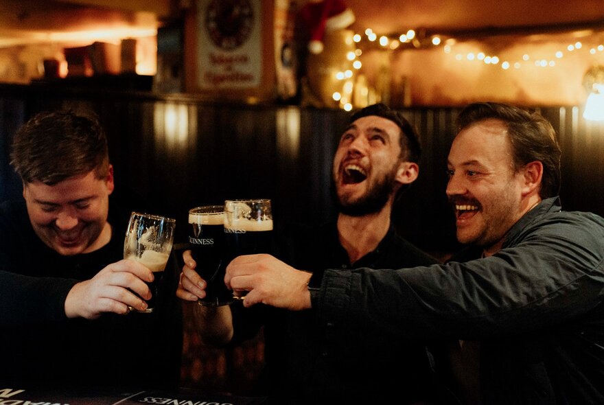 Three friends laughing and enjoying Guinness pints at P.J. O'Brien's Irish Pub.