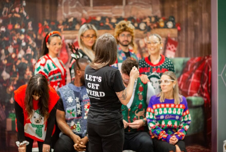 People dressed in ugly Christmas jumpers about to get their photo taken. 