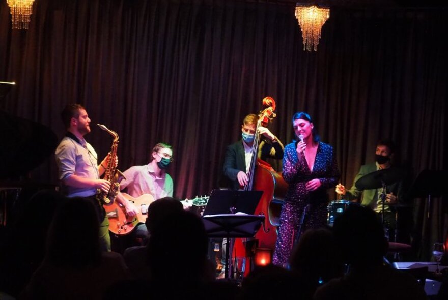 A jazz band on stage in front of a dark purple curtain.