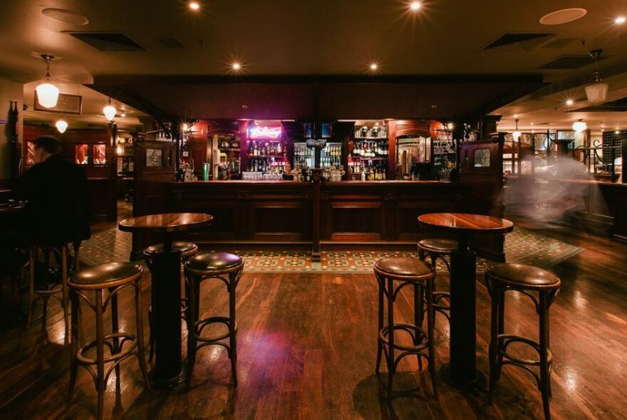 Wooden interior on Turf Sports Bar showing bar service area, high bar tables and high stools.