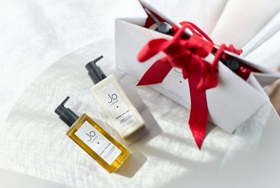 Bottles of perfume and ribbon-wrapped gift bag.