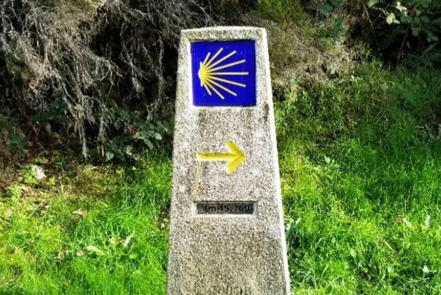 A stone marker on the side of a walking track for the Camino de Santiago, a network of pilgrimage walking routes leading to a shrine in Spain.