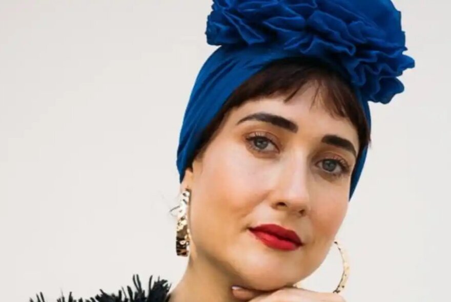 Dark-haired woman with blue headscarf and large hoop earrings.