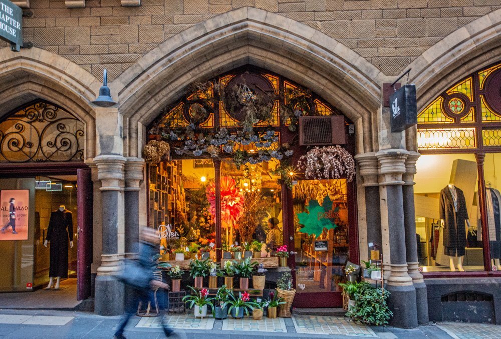 A person is walking in front of a florist.