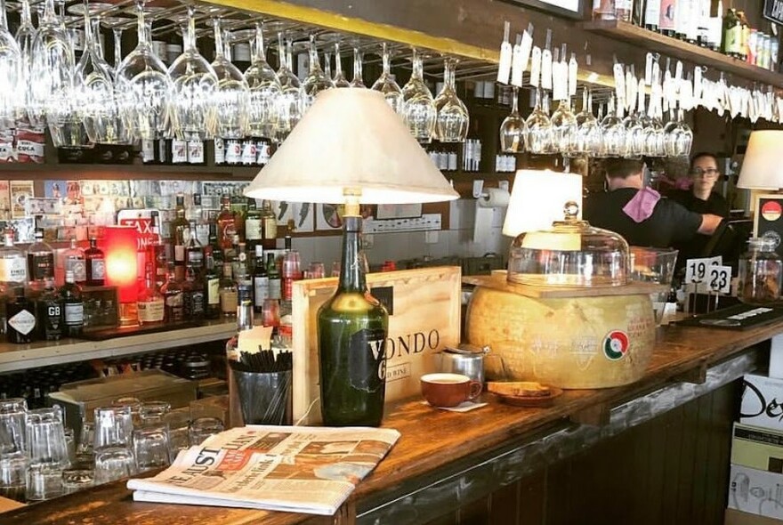 Newspaper on the bar counter and a lot of hanging glasses.