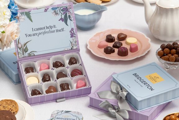 A selection of gourmet chocolates, biscuits and tea, seen from above on a table with floral decorations.