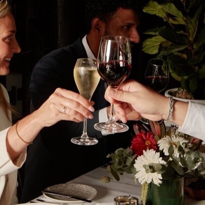 Woman with blonde hair clinking glasses at a table.