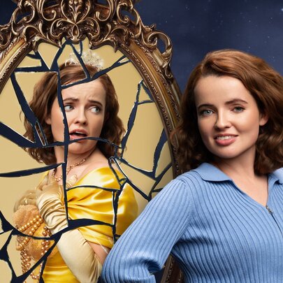 Comedian Roisin McAlinden posing in front of a gilt-framed, shattered oval mirror showing her reflection as a sad fairy tale princess.