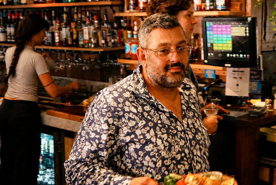 A man looking satisfied walking away from a bar with a plate of food
