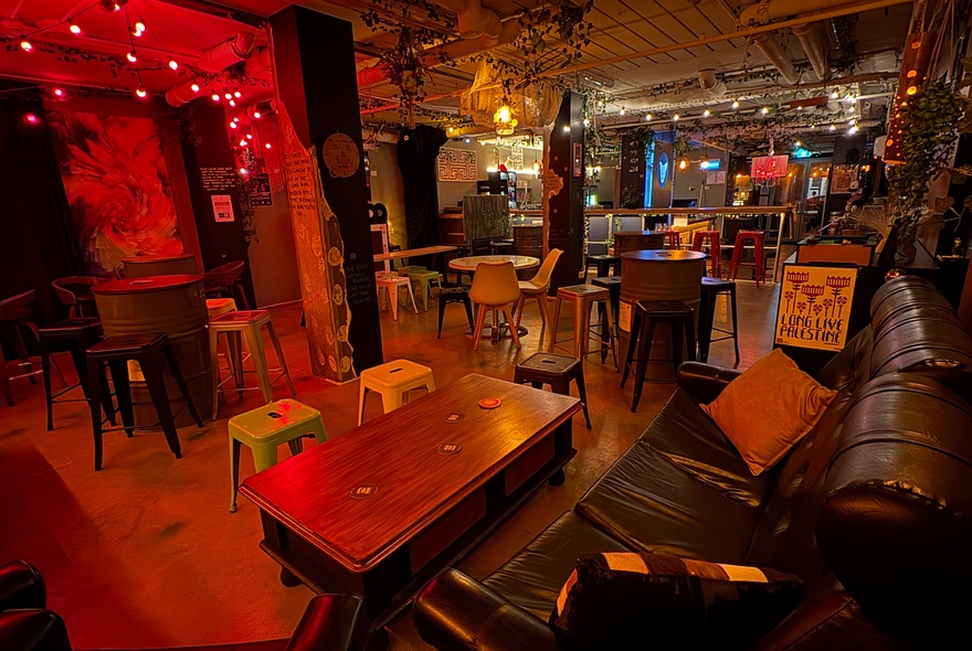 Venue with couches, armchairs, stool seating and red fairy lights.