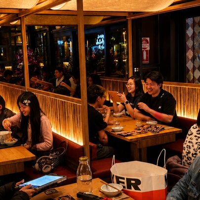 Booth Japanese dining with low lighting and youthful customers.