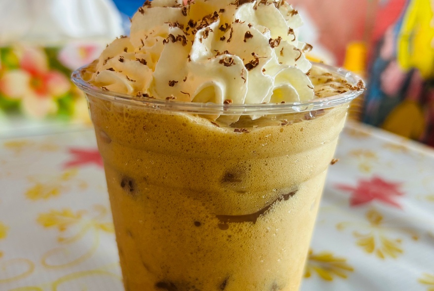 Close up photograph of an iced coffee with cream and chocolate sprinkles on top.