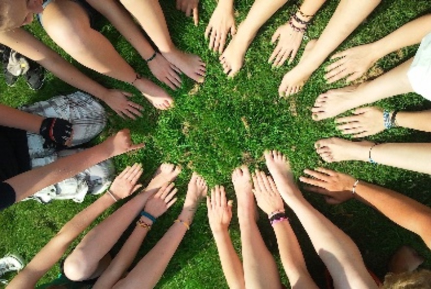 Hands reaching into a centralgrassy area.