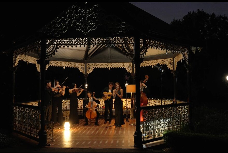A string quartet playing in a rotunda at night. 