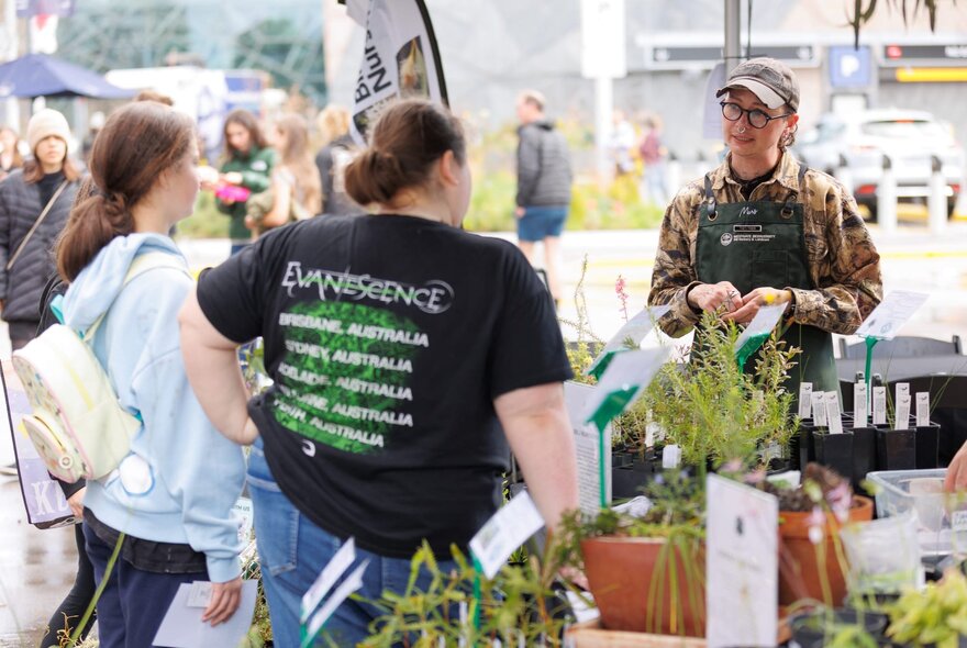 People at a market stall selling plants.