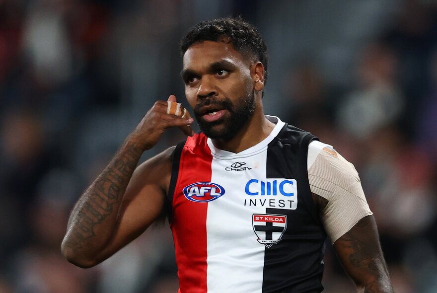 A St Kilda AFL player celebrating having scored a goal, his fingers in a gesture near his ear.