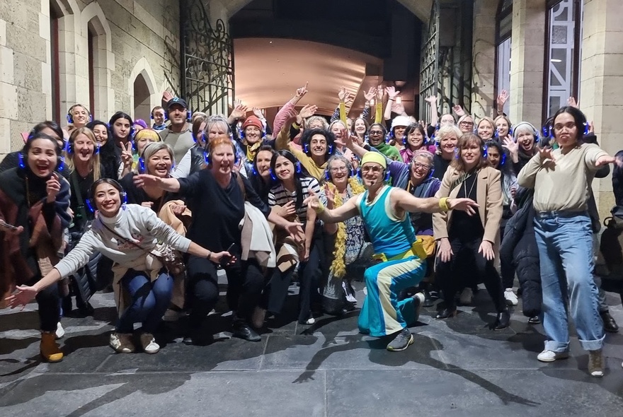 Group of people wearing headphones and posing in a dance-style move, in a Melbourne city laneway.