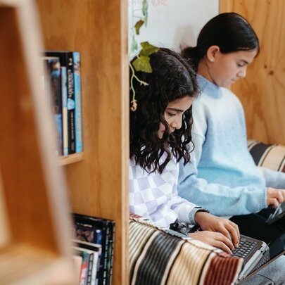 Two young teenagers studying together in a library space as part of a creative writing workshop.