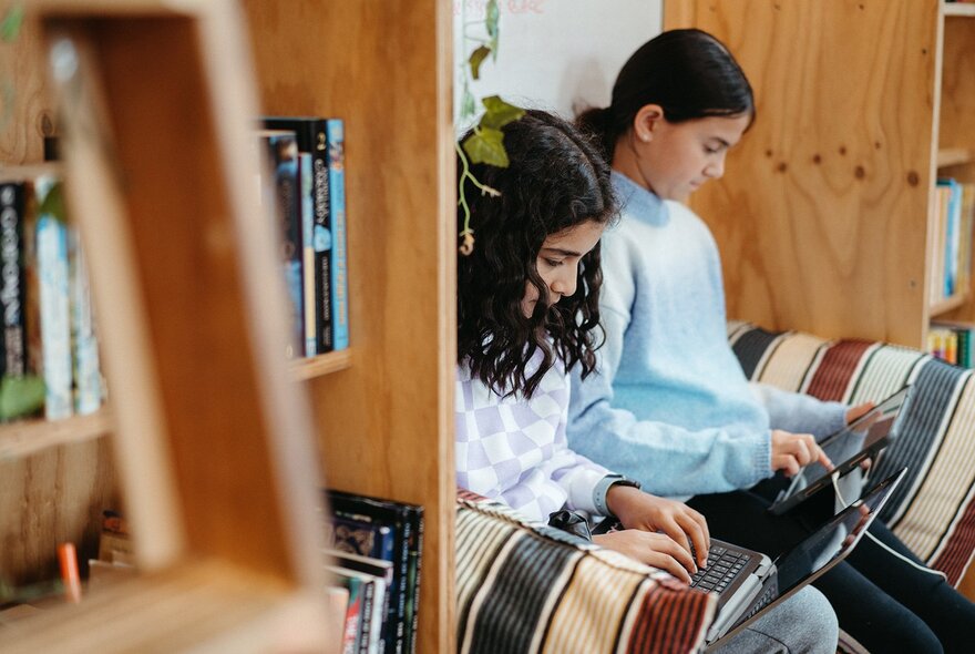 Two young teenagers studying together in a library space as part of a creative writing workshop.
