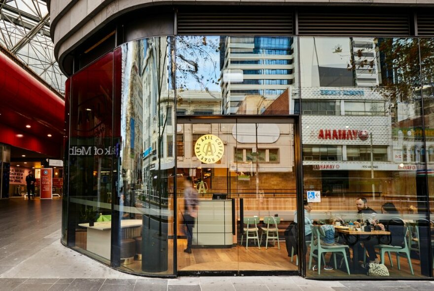 The exterior of a glass walled cafe inside a covered arcade.