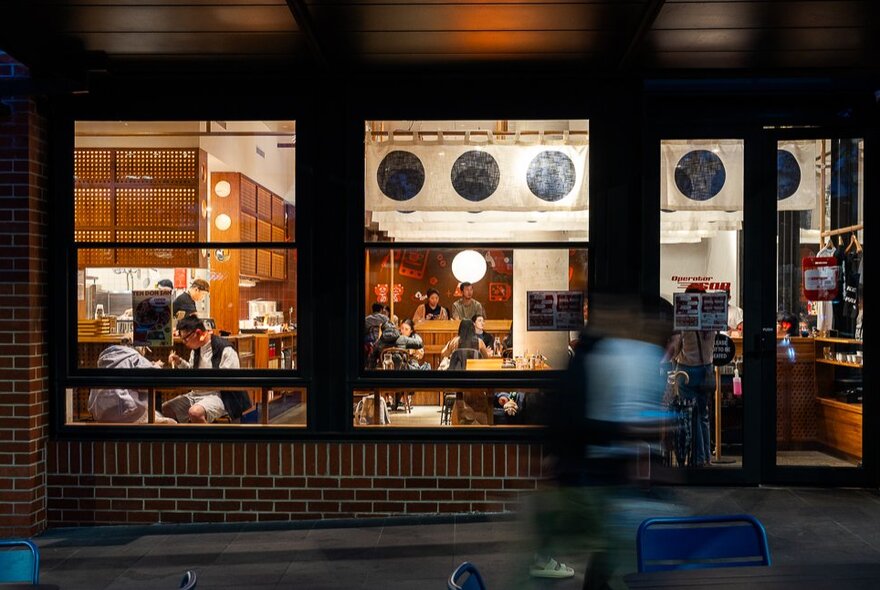The exterior of a restaurant at night, seen from the street.