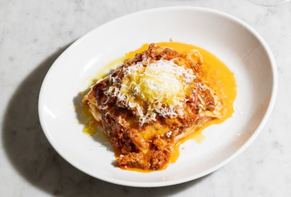 A slice of lasagne with lots of sauce and grated parmesan on top.