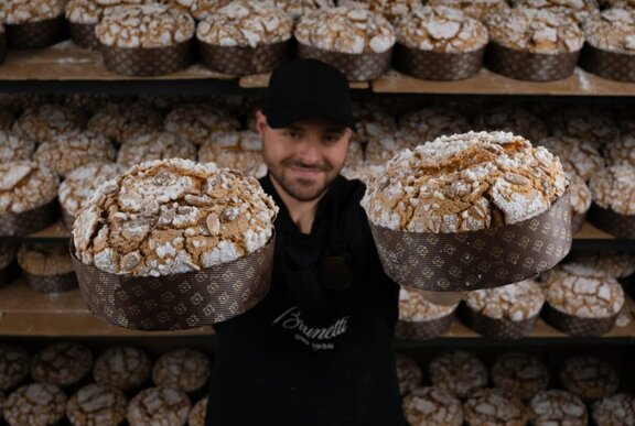 An employee at Brunetti's holding up two panettone festive cakes.
