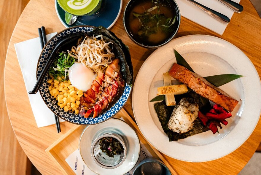 Overhead view of a table in a cafe with plates of food, glasses and cutlery.