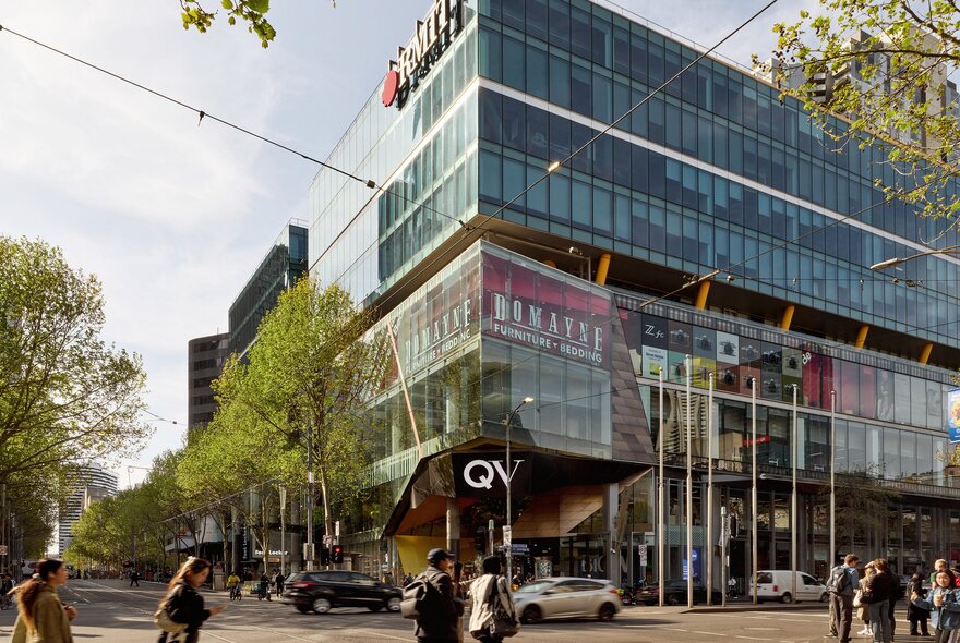 People crossing in front of QV shopping centre on the corner of two busy streets.