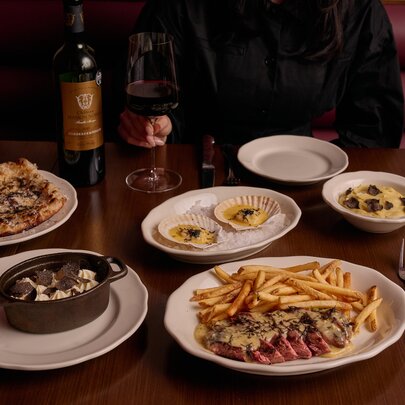 A spread of dishes including steak, scallops and bread all topped with truffles.