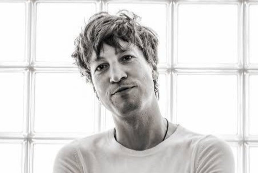 Black and white image of singer Marlon Williams with tousled hair and a slight smile.