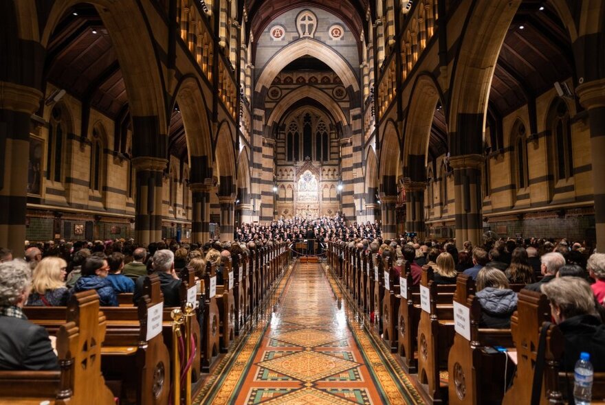 Looking down the central nave of St Paul’s Cathedral towards the altar, with people seated in the pews.
