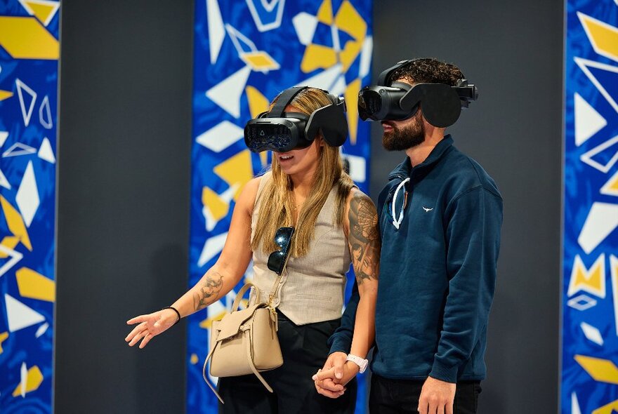 People wearing VR goggles looking at graphic shapes displayed in a gallery.