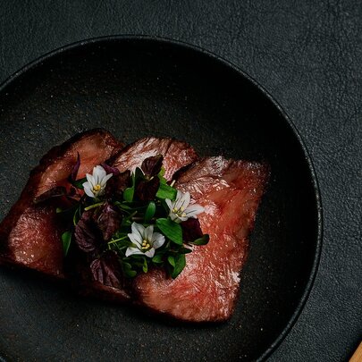 Slabs of raw marbled Wagyhu beef on a black background.