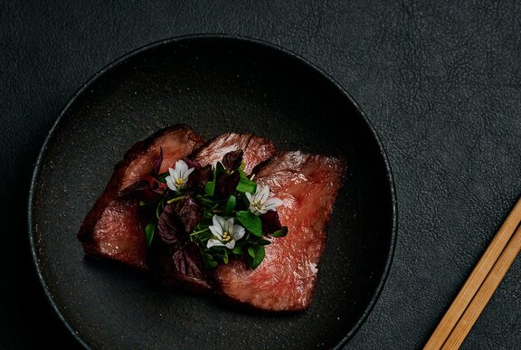 Slabs of raw marbled Wagyhu beef on a black background.