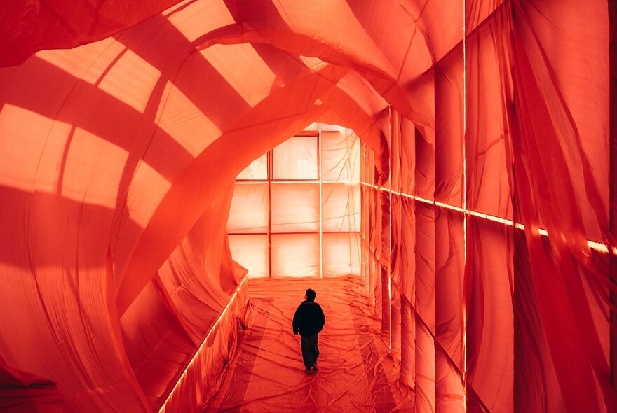 A person walking through a giant red fabric tunnel.