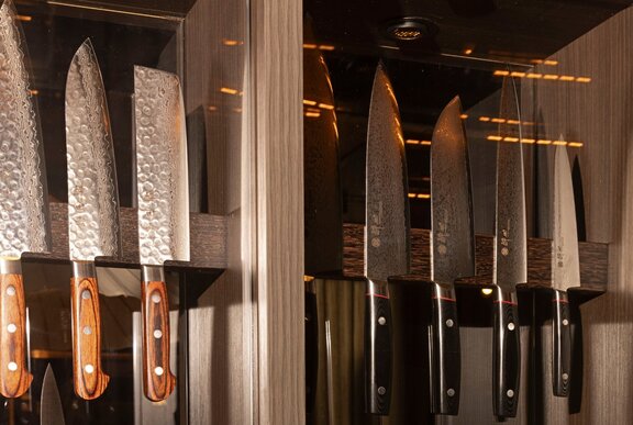 Rows of Japanese knives for sale on a magnetic rack in a shop.
