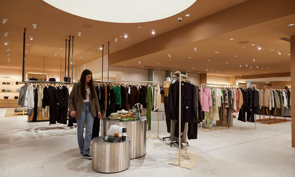 A stylish fashion boutique with a woman browsing a display.