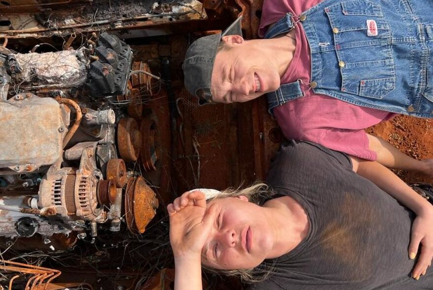 Two hound men in caps lay in a rusted-out car.