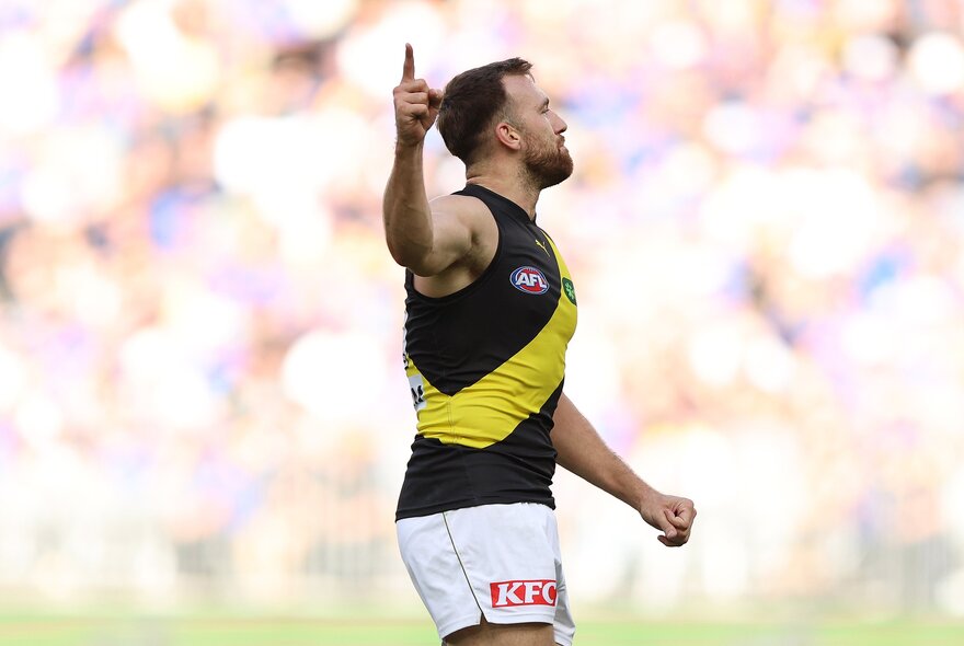 A cheering Richmond AFL football player with a clenched fist and a raised arm on the field during a match.