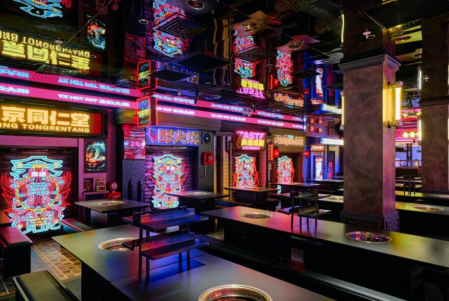 The brightly coloured futuristic, and neon interior of YX Hot Pot, with individual hot pot tables and bench seating.  