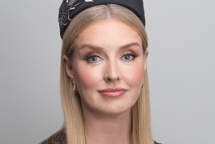 A headshot of a woman wearing a black fascinator.