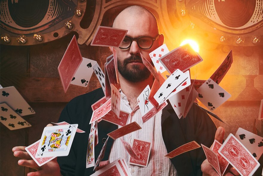 A person skillfully throwing a deck of playing cards into the air in a theatrical setting.